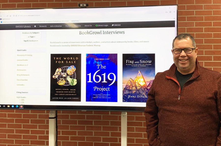 Caption: SWOSU librarian Frederic Murray stands next to the webpage for his podcast,“BookGrowl.” 